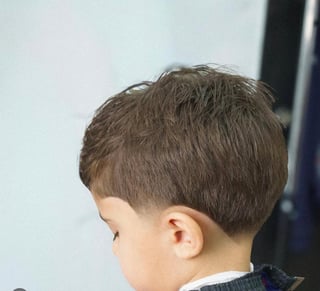 Side profile of a young boy with short brown hair against a white wall
